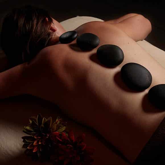 A person lays face town with six hot, black stones in a line down their back at a Colorado spa in Vail.