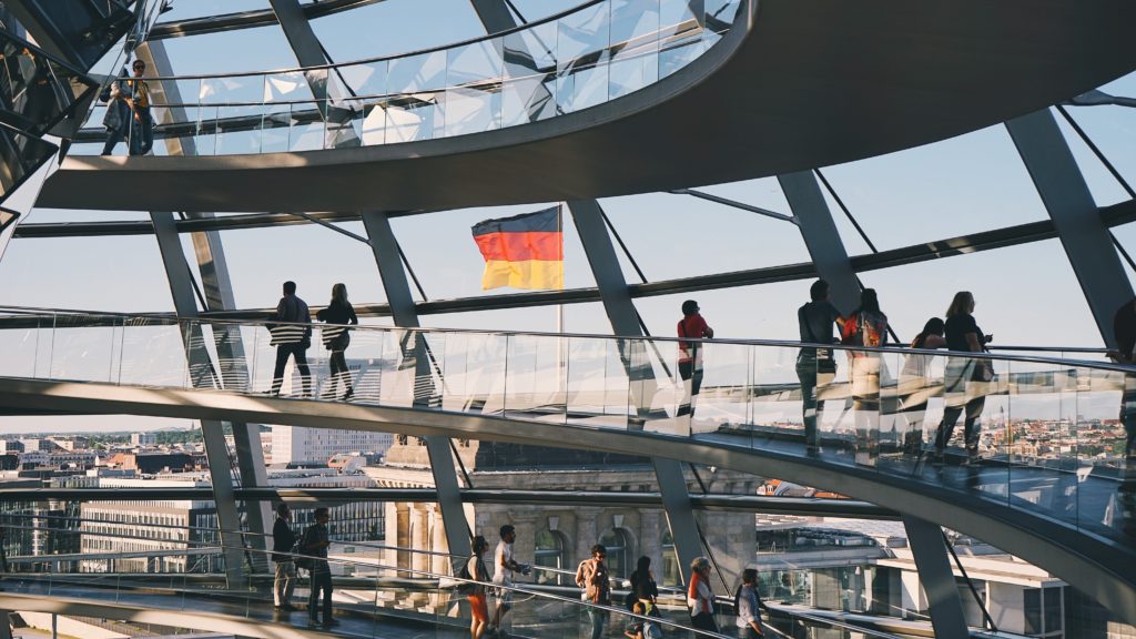 A group of people standing on a glass walkway in the reichstag building.
