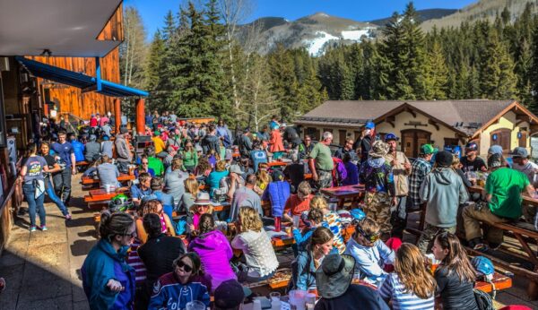 A crowd of skiers gather on the outdoor patio of Garfinkel's in Lionshead as the day winds down. They socialize and soak up the sunshine with the bright blue sky above.