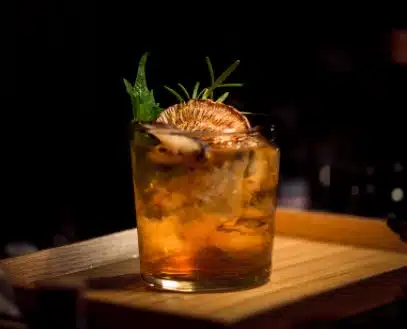 A cocktail is sitting on top of a wooden tray.