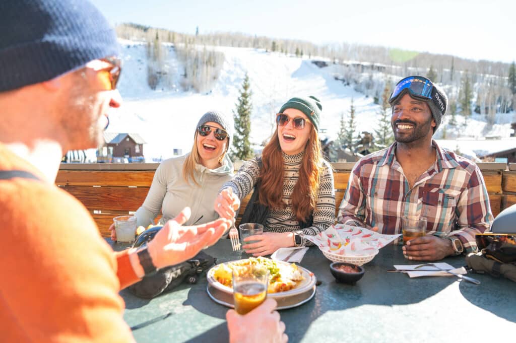 Four friends an enjoy an apres meal outside on a terrace in Vail, Colorado.