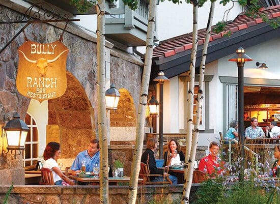 A group of people promoting sustainability sitting at tables outside of a restaurant.