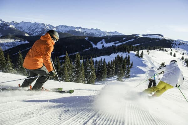 three skiers slide down a well-groomed trail during a ski lesson in Vail