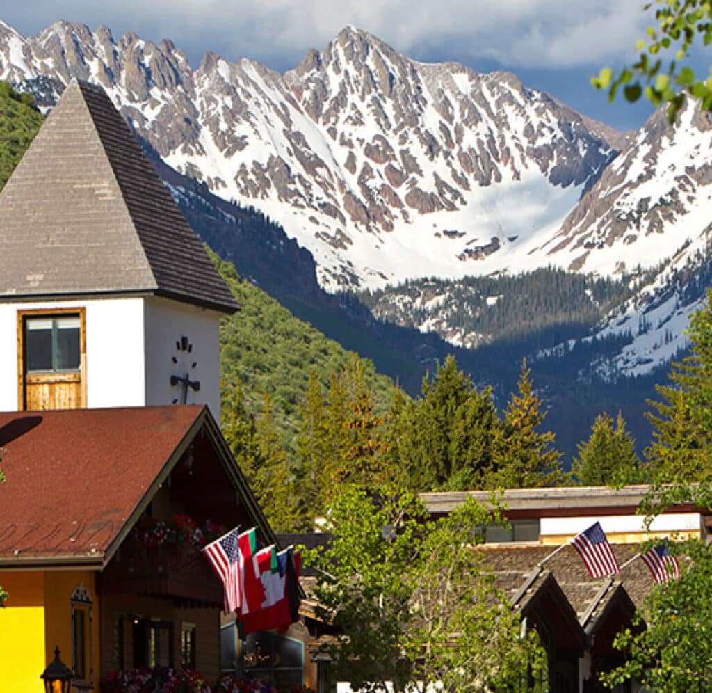 The side of a mountain covered in snow rises above a Bavarian-style chalet in Vail Village.
