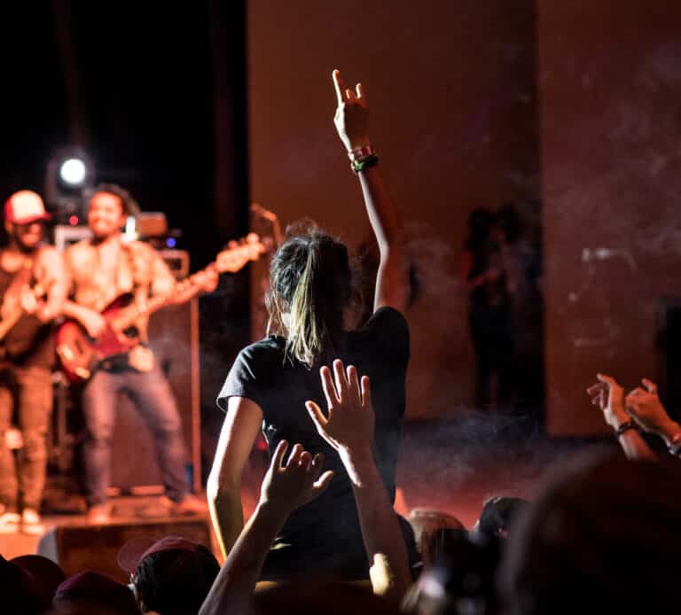 A group of people at a dark concert in Vail raising their hands in the air.