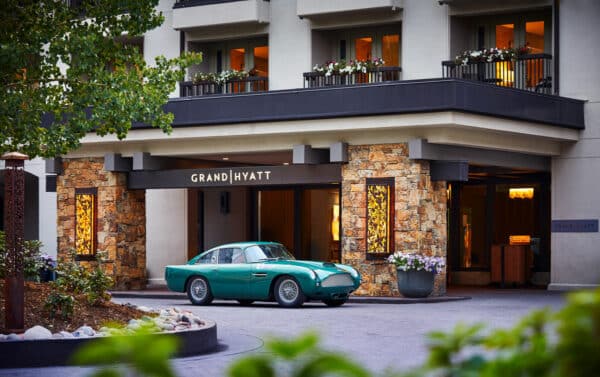 A minty-green classic car parks in front of the Grand Hyatt Vail in West Vail. Summery planters decorate the balcony above the front entrance.