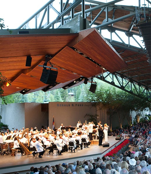 A group of performers wearing white uniforms plays classical music on a stage at The Amp in Vail, Colorado.