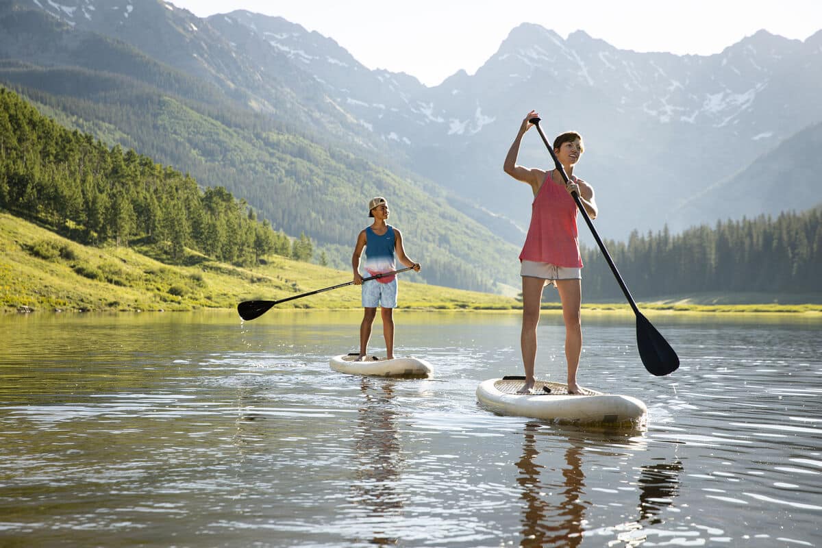 Young man and woman stand-up paddle boarding in Vail