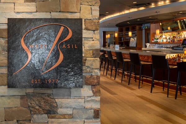 From the entrance at Sweet Basil, in Vail, Colorado, you can see a sleek, gray bar with a row of tall black bar chairs.