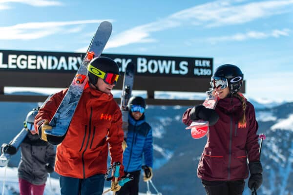 A group of skiers, dressed in helmets, goggles and warm jackets, walk back from Vail's Legendary Back Bowls.