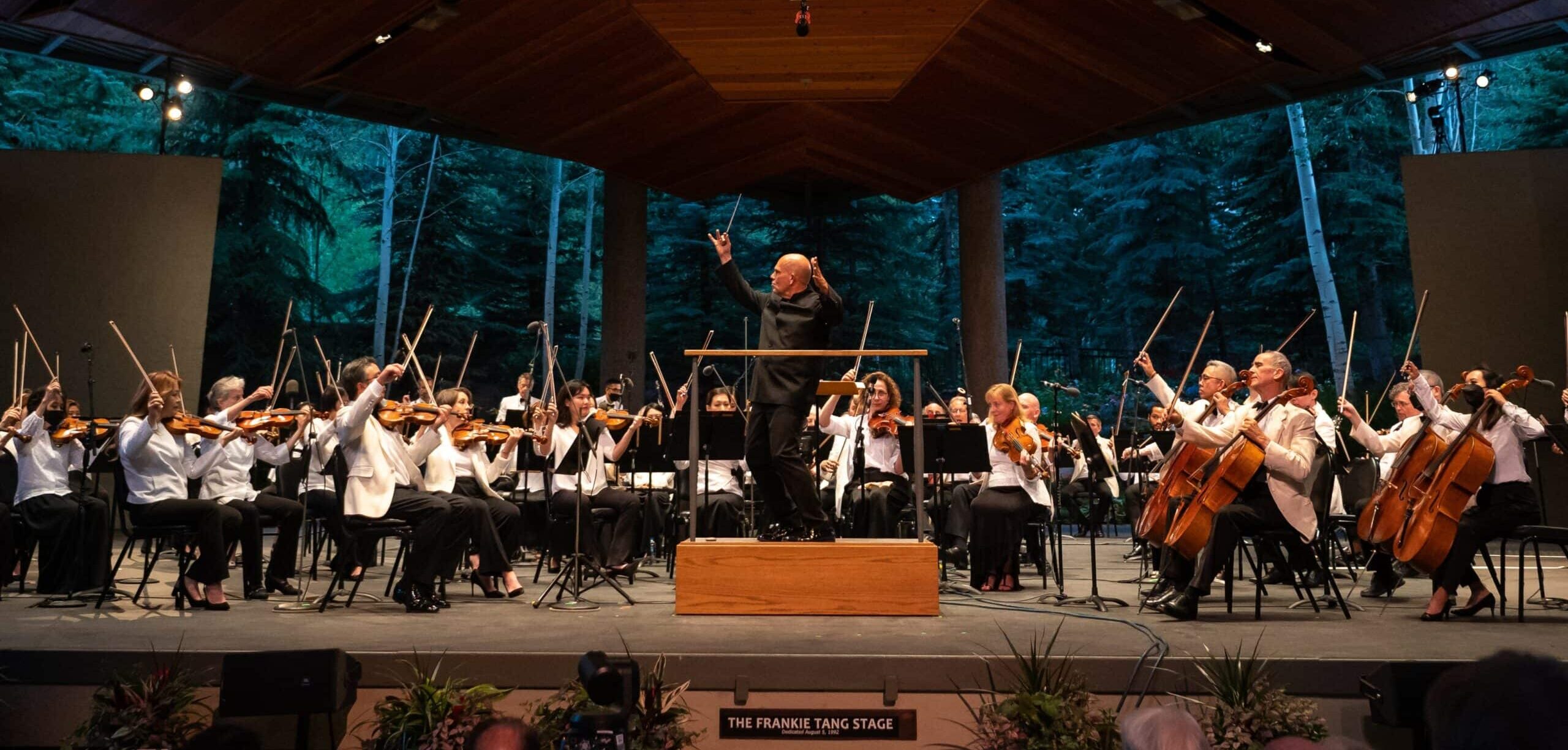 Symphony orchestra performing in a wooded area.