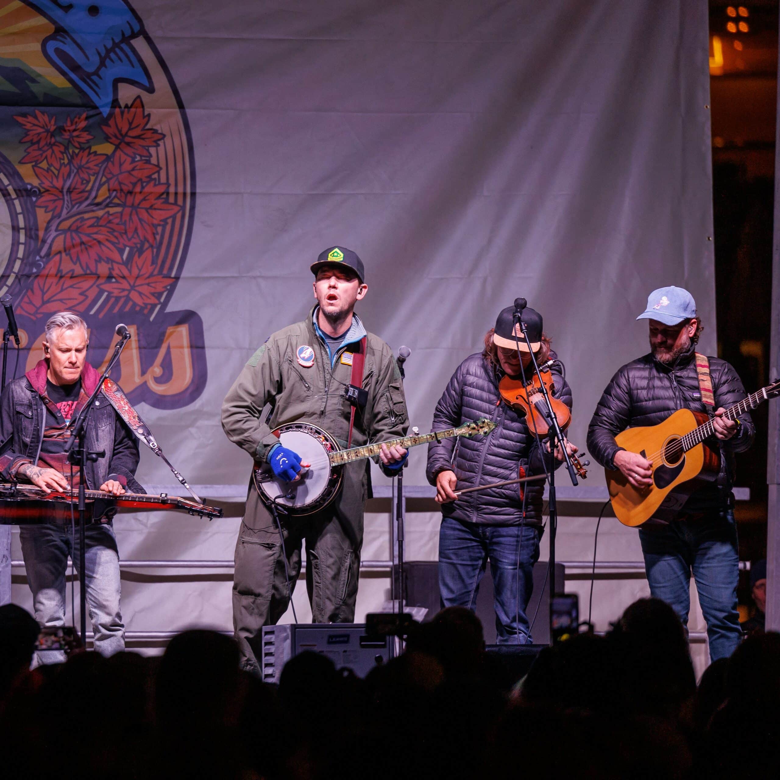 A group of men playing banjos and guitars on a stage.