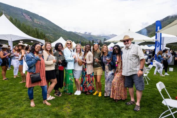 A group of people pose for a picture with wine glasses at the Vail Wine Classic event in Colorado.