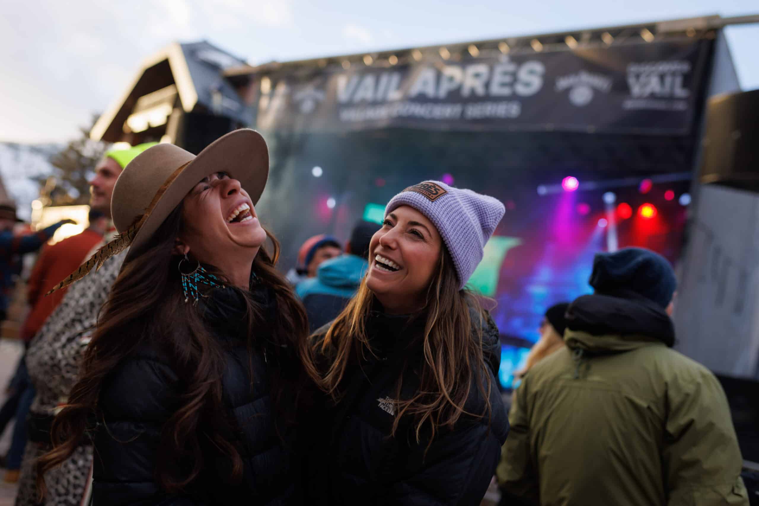 Two girls laughing and dancing at a Vail Apres concert in Vail Village in the winter