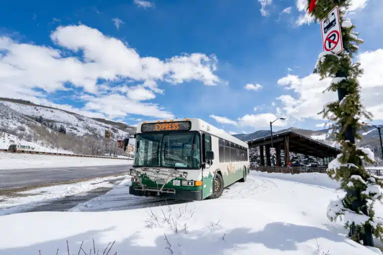 Town of Vail bus stopped at a bus stop on a clear winter day with snow on the ground.