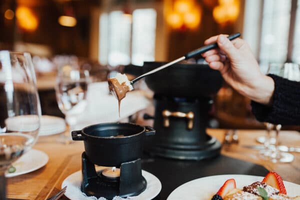 Marshmallow being dipped in fondue chocolate at Swiss Chalet in Vail, Colorado.