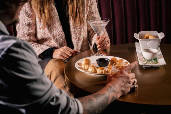 Two people sit around a table in Vail's Chasing Rabbit, with cocktails and some food.