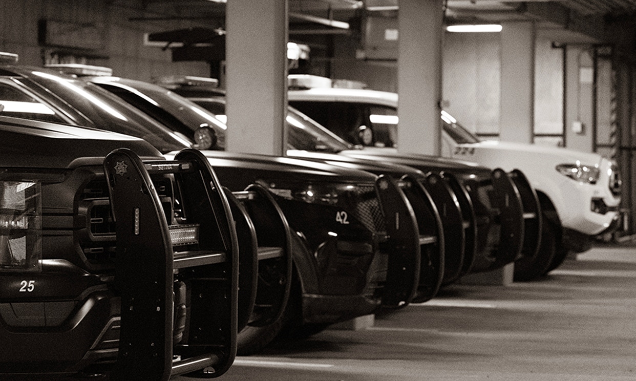 Image of black cars and one white car parked in an underground garage