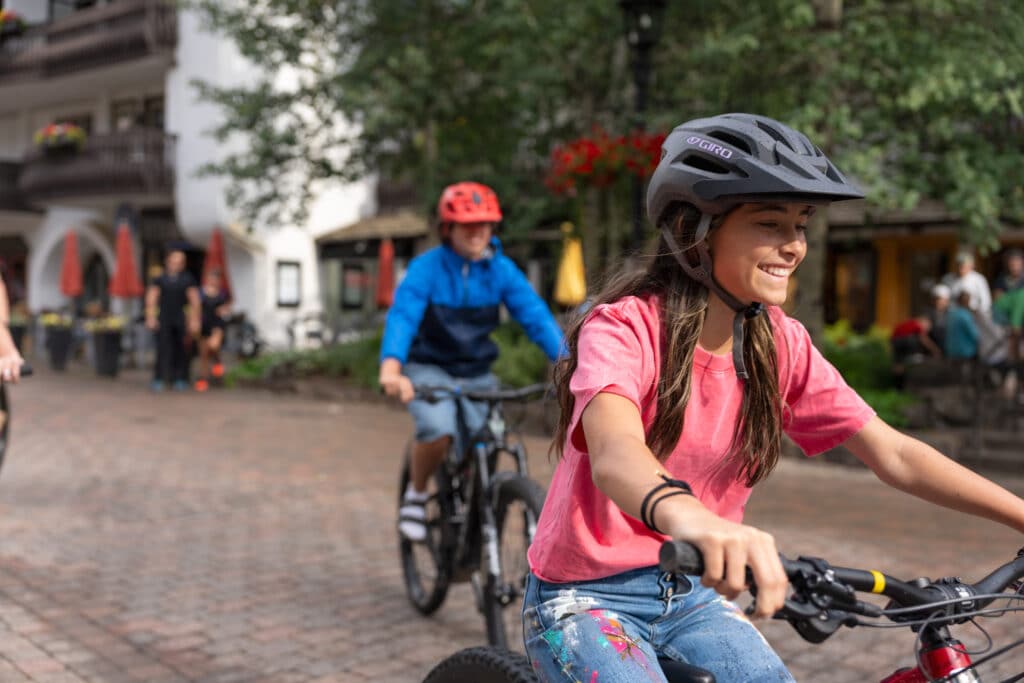 Closeup shot of a young girl smiling as she rides a bike through the streets of Vail.