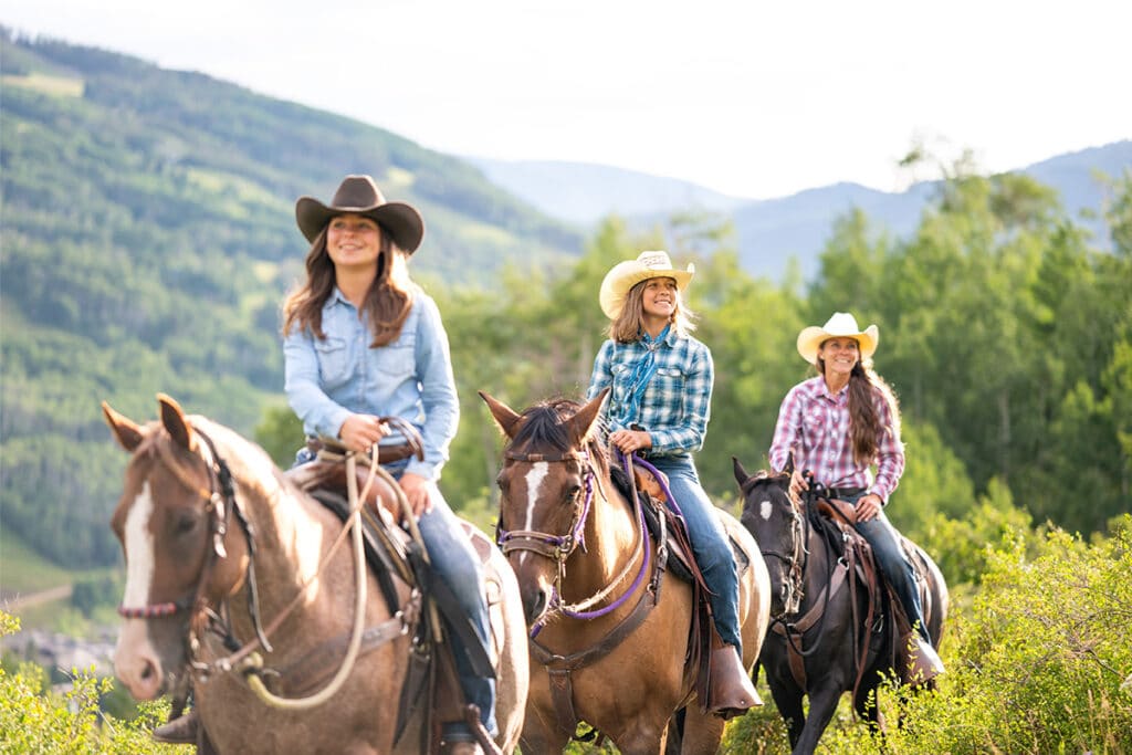 Three people ride three horses through the alpine backcountry near Vail, Colorado.