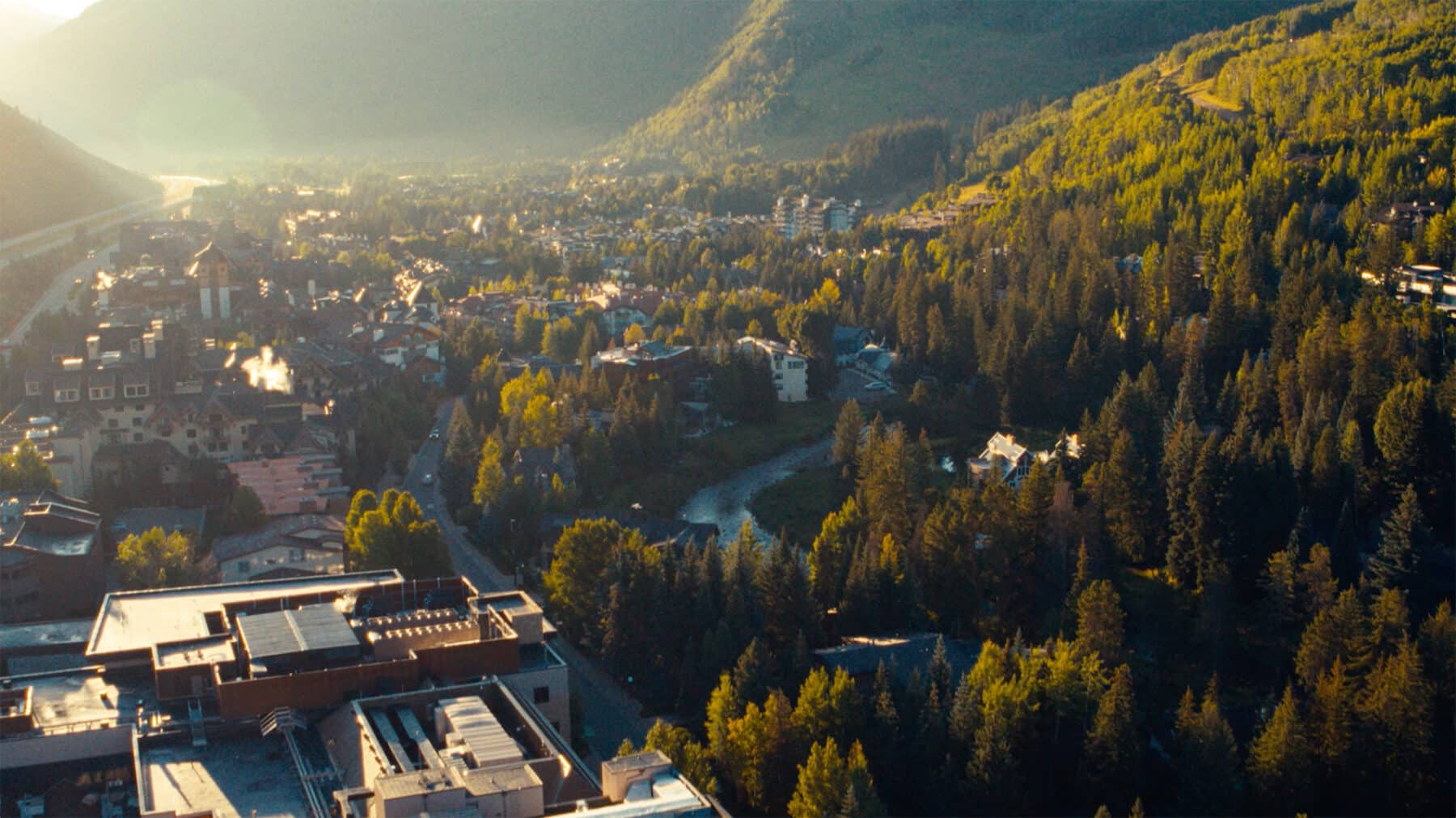 Aerial shot looking over Vail with golden light shining over the trees.