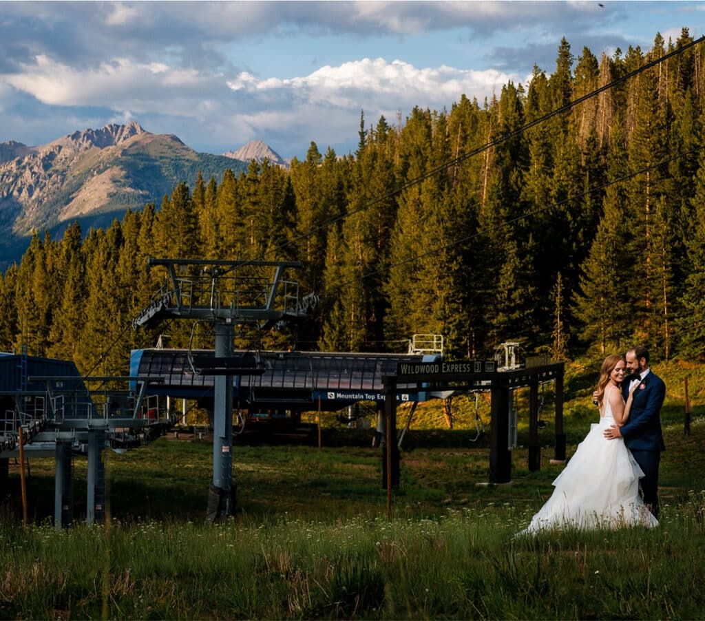 Bride and groom pose near a chairlift at the top of Vail Mountain