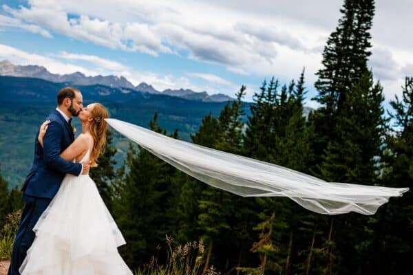 Bride and groom kiss at the top of vail mountain