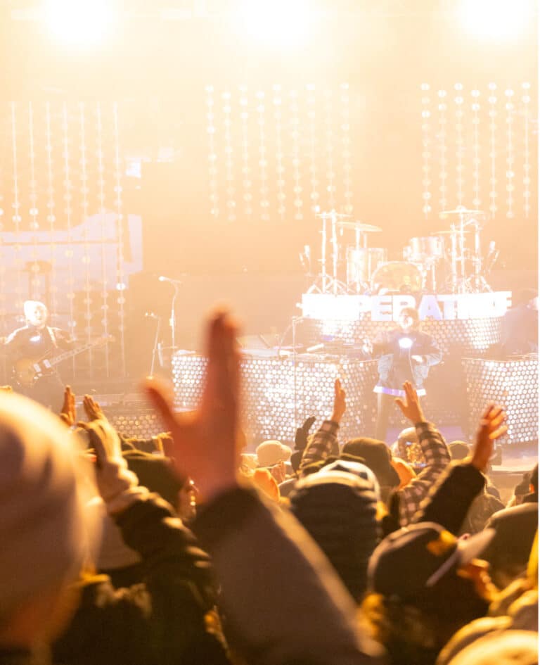 A crowd cheers on a band on stage at a concert.