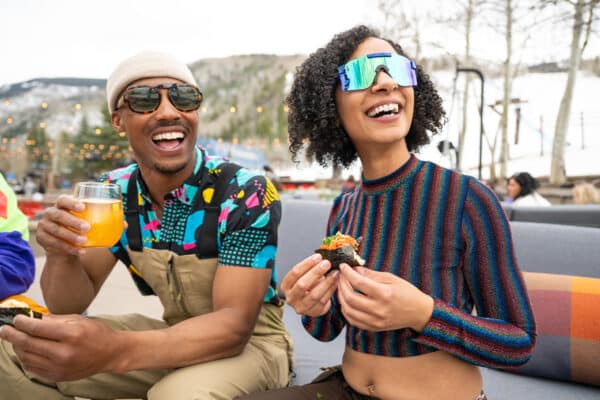 Two people snack on sushi while wearing their ski gear at Avanti F&B Vail in Vail, Colorado.