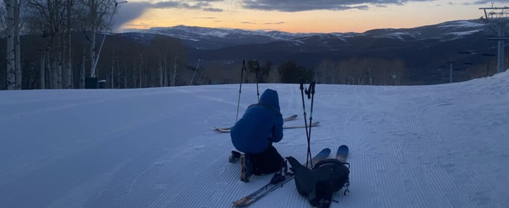 An uphill skier on Vail Mountain in Colorado preps their gear for the downhill journey.