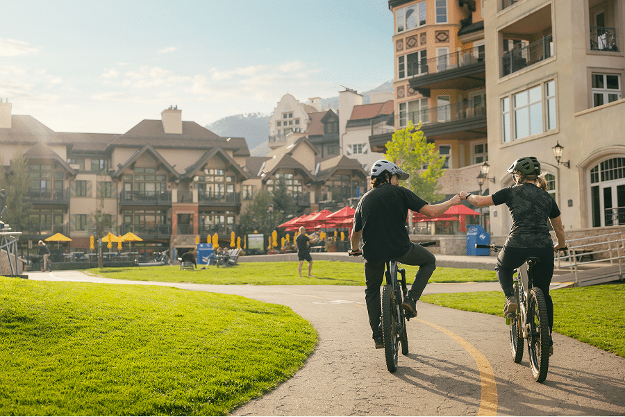two people ride bikes through the villages of vail