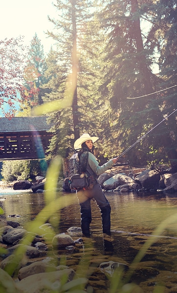 women fly fishes under a bridge