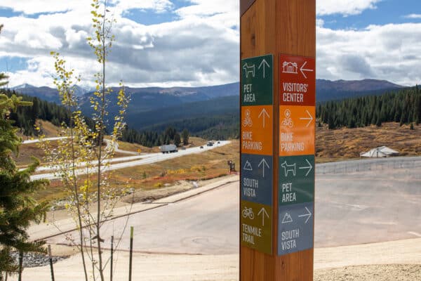 Signs for facilities at Vail Pass Rest Area, with mountains and a highway in the background