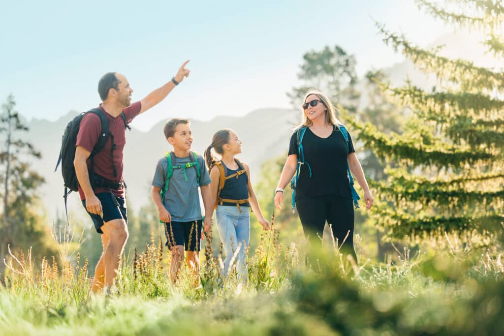 Family hiking together on a mountain trail in Vail with Gore Range in background