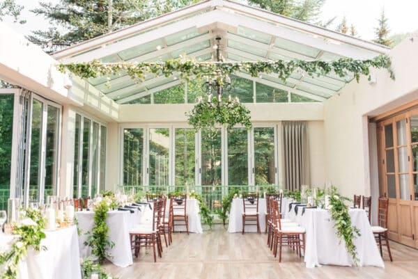 Sonnenalp Hotel readies for a wedding with greenery and garlands strewn over tables with white tablecloths and from the chandelier.