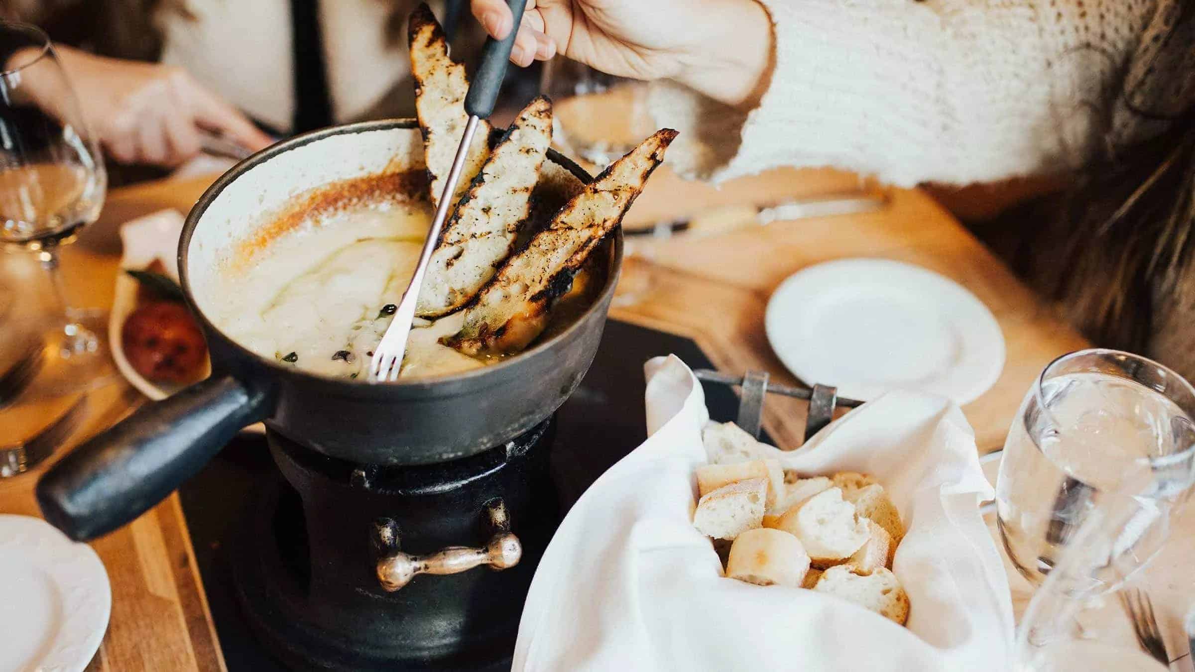Woman dipping bread in fondue pot a the Swiss Chalet restaurant. 